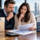 Two adults review life insurance options at a financial planning desk, comparing term life and whole life insurance costs and coverage.